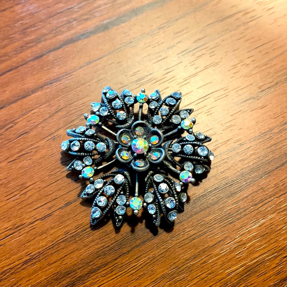 Brooch with dark metal base and sparkle stones
